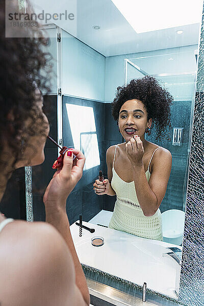 Frau schminkt sich zu Hause vor dem Spiegel
