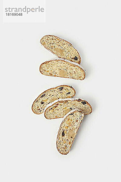 Pieces of Christmas stollen cakes with dried fruits arranged on white background