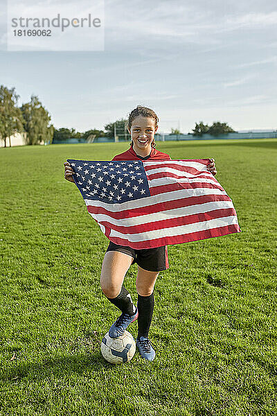 Glückliches Mädchen mit amerikanischer Flagge auf dem Feld