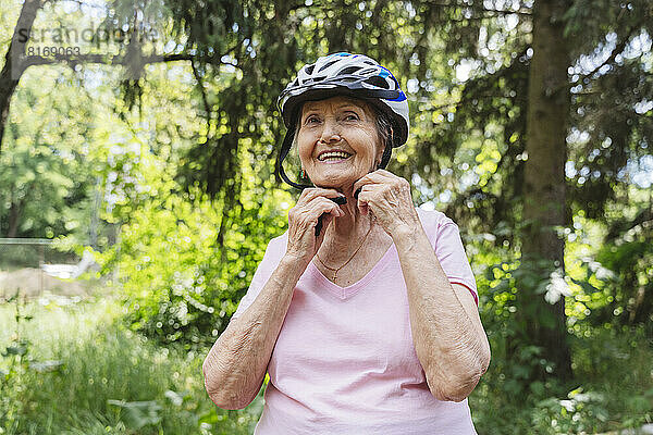 Lächelnde ältere Frau mit Fahrradhelm im Park