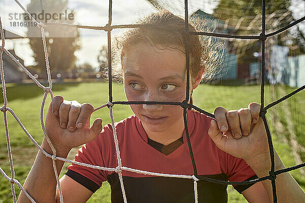 Mädchen wird an einem sonnigen Tag durch das Netz auf dem Sportplatz gesehen