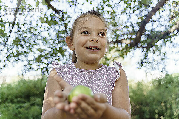 Nettes Mädchen hält grünen Apfel im Park