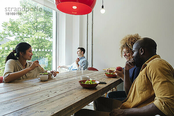 Geschäftsleute essen gemeinsam im Lehrerzimmer eines modernen Büros gesund zu Mittag