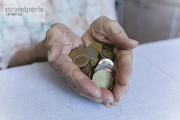 Münzen in den Händen einer älteren Frau zu Hause
