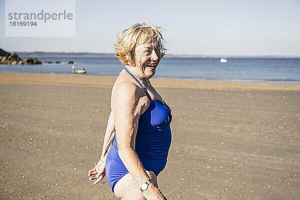 Glückliche ältere Frau  die an einem sonnigen Tag am Strand genießt