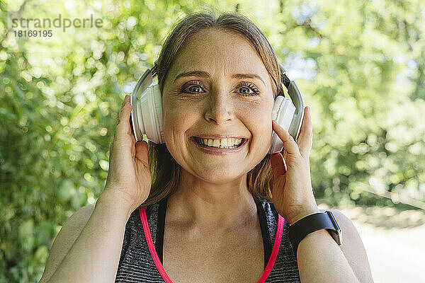 Lächelnde Frau  die über Kopfhörer Musik hört