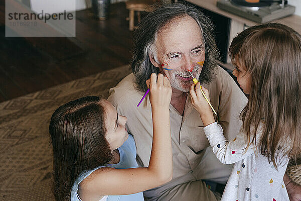 Verspielte Kinder haben Spaß daran  zu Hause die Nase des Großvaters zu bemalen