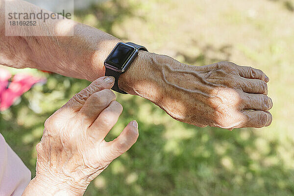 Hände einer älteren Frau  die an einem sonnigen Tag eine Smartwatch trägt
