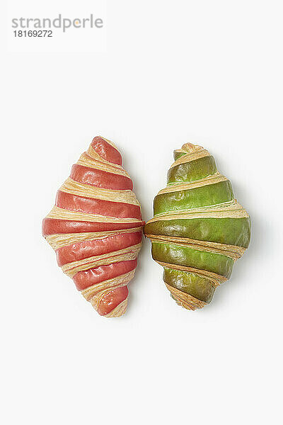 Pink and green striped croissants on white background