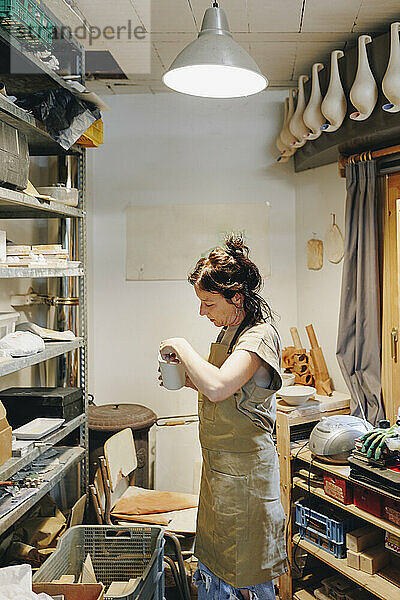 Töpfer untersucht Keramik  die in der Werkstatt am Regal steht