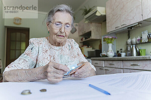 Senior woman counting paper currency at home