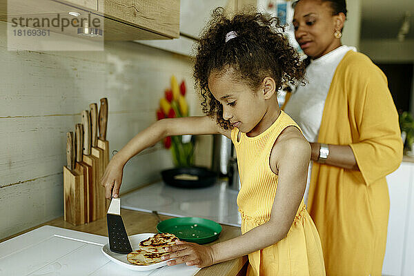 Mädchen hilft Mutter beim Kochen an der Küchentheke