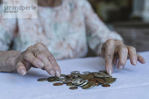 Ältere Frau zählt zu Hause Münzen auf dem Tisch