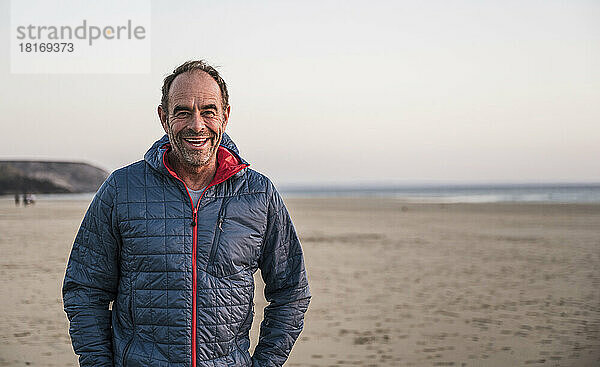 Cheerful mature man wearing jacket standing at beach