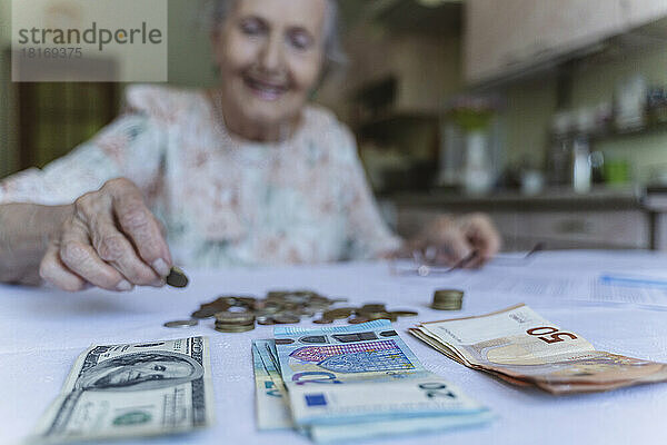 Ältere Frau arrangiert Ersparnisse auf dem Tisch zu Hause