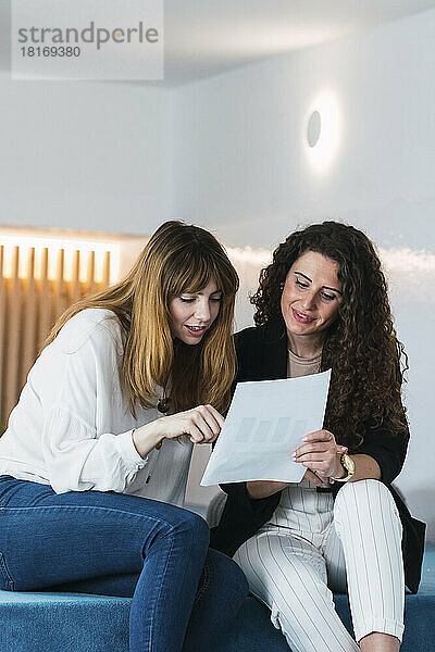 Zwei Geschäftsfrauen lesen ein Dokument im Büro-Lounge
