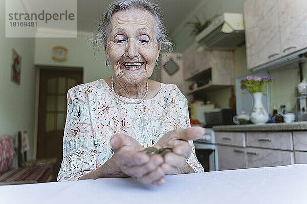 Glückliche ältere Frau  die Münzen betrachtet