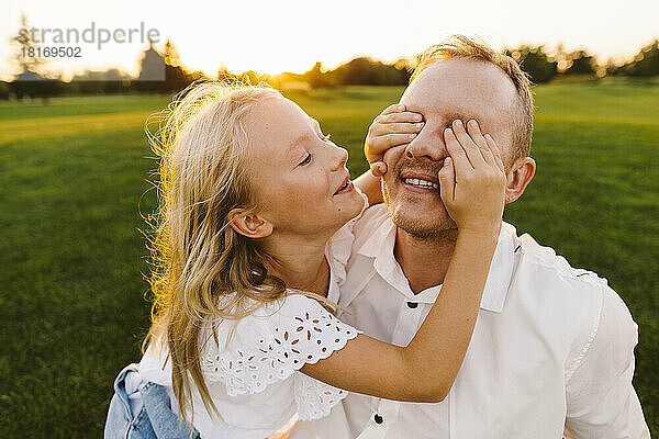 Glückliche Tochter bedeckt Vaters Augen im Park