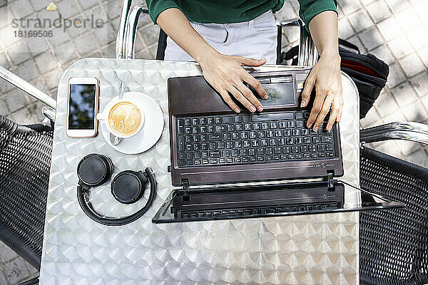 Freelancer working on laptop at sidewalk cafe