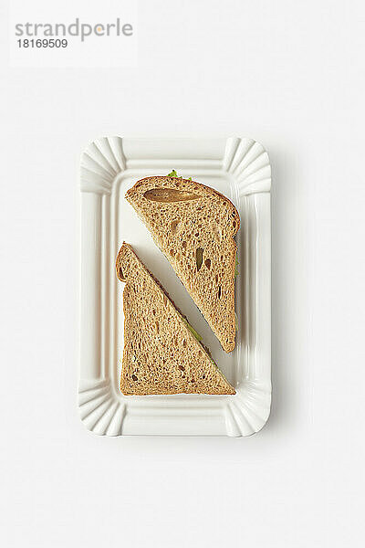Schwarzbrot-Sandwich auf Tablett vor weißem Hintergrund