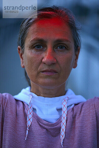 Ernsthafte Frau mit Reflexion von rotem Licht im Gesicht