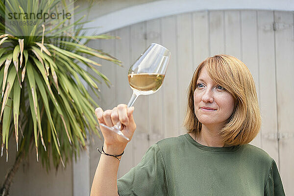 Reife Frau schaut vor der Wand auf Weißwein