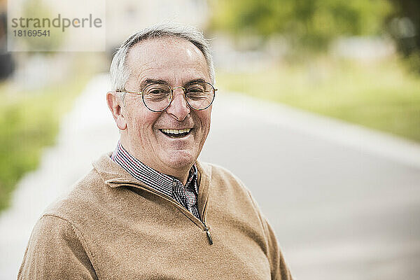 Glücklicher älterer Mann mit Brille auf Fußweg