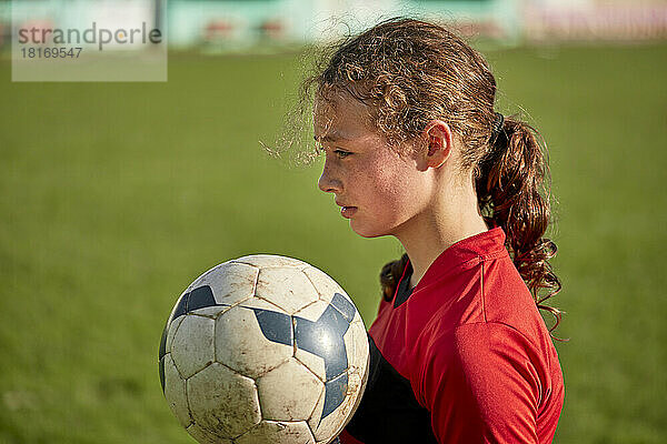 Nachdenkliches Mädchen mit Fußball an einem sonnigen Tag