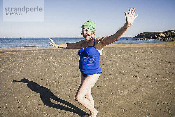 Ältere Frau im Badeanzug hat Spaß am Strand