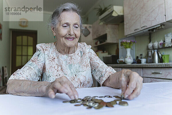 Lächelnde ältere Frau  die zu Hause Münzen zählt