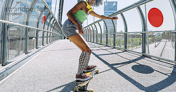 Junge Frau tanzt Longboard auf Brücke