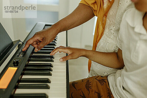Hand einer Frau  die ihrem Sohn das Klavierspielen beibringt