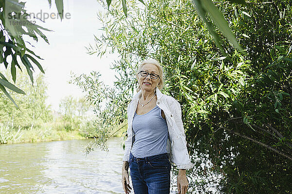 Ältere Frau mit Brille steht neben Pflanzen