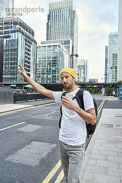 Mann mit Einweg-Kaffeetasse begrüßt Fahrt auf der Straße in der Stadt