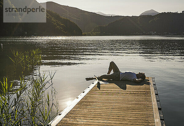 Reifer Mann entspannt sich am Laptop am Steg über dem See