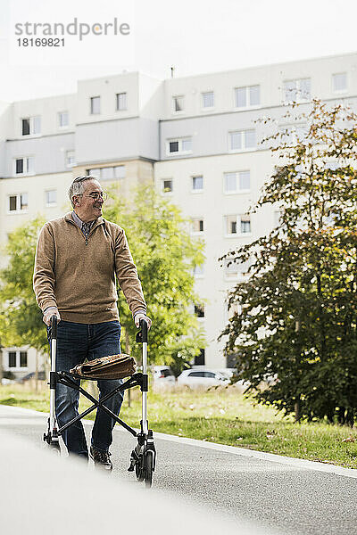 Älterer Mann mit Gehhilfe geht auf Fußweg