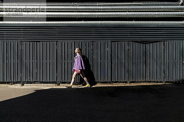 Frau läuft an einem sonnigen Tag vor einer Mauer