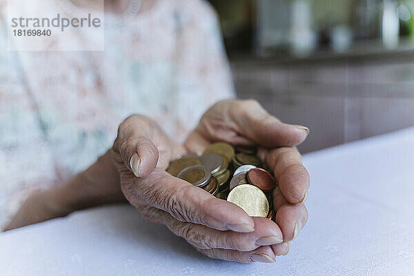 Ältere Frau hält zu Hause Münzen über den Tisch