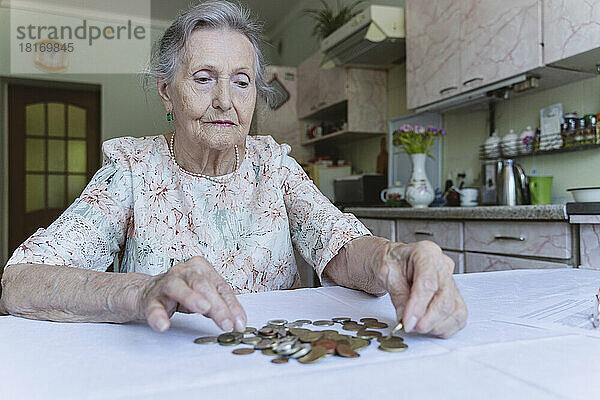 Ältere Frau zählt Ersparnisse auf dem Tisch zu Hause