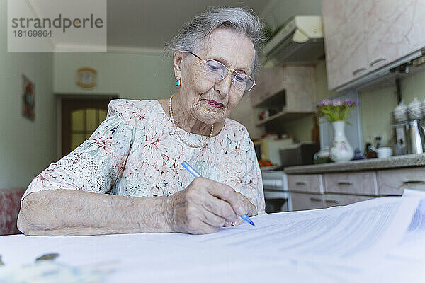 Ältere Frau unterzeichnet Investitionsdokumente auf dem Tisch