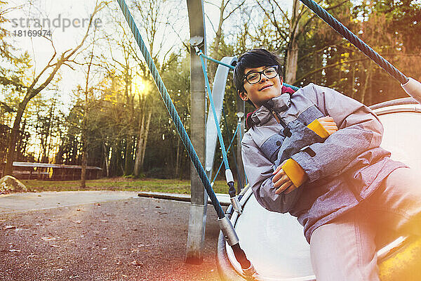 Ein Junge spielt auf einer Untertasse auf einem Spielplatz im Herbst; Langley  British Columbia  Kanada