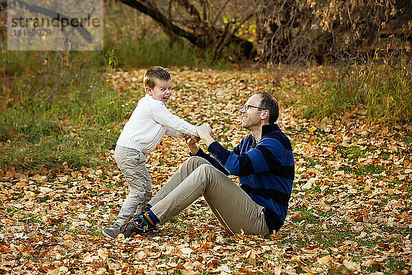 Ein Vater spielt mit seinem Sohn während eines Familienausflugs in einem Stadtpark während der Herbstsaison; St. Albert  Alberta  Kanada