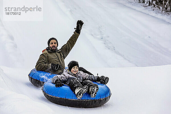 Vater und Sohn beim Tubing auf einem Skihügel; Fairmont Hot Springs  British Columbia  Kanada