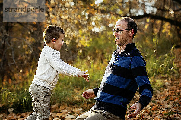 Ein Vater spielt mit seinem Sohn während eines Familienausflugs in einem Stadtpark während der Herbstsaison; St. Albert  Alberta  Kanada