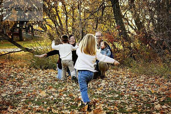 Junge Familie mit drei Kindern  die jüngste Tochter mit Down-Syndrom  vergnügt sich gemeinsam in einem Stadtpark während der Herbstsaison; St. Albert  Alberta  Kanada