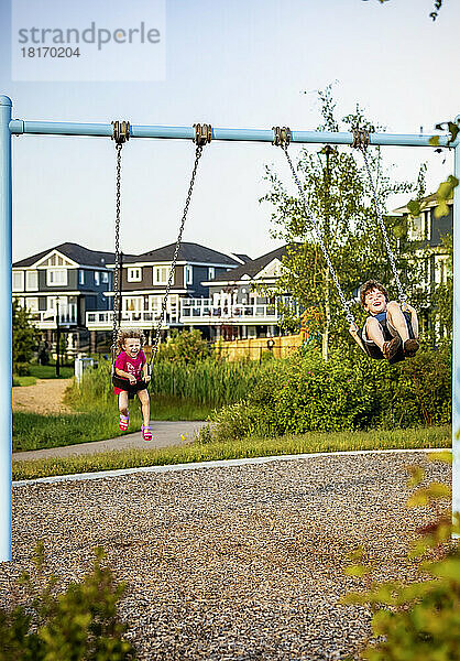 Junges Mädchen und Junge spielen auf einer Schaukel auf einem Spielplatz; St. Albert  Alberta  Kanada