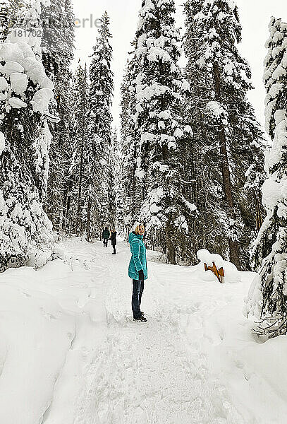 Eine Wanderin blickt auf einem schneebedeckten Wanderweg rund um den Emerald Lake im Winter im Yoho National Park in British Columbia  Kanada  in die Kamera.