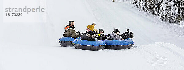 Familienmitglieder  die gemeinsam im Tandem einen Skihügel hinunterfahren; Fairmont Hot Springs  British Columbia  Kanada