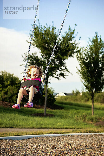 Mädchen im Vorschulalter schwingt auf einer Schaukel auf einem Spielplatz; St. Albert  Alberta  Kanada