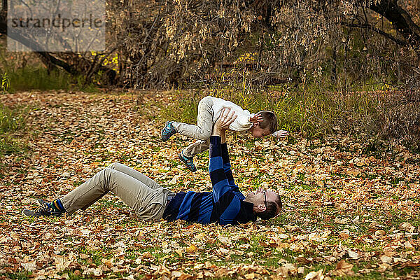 Ein Vater spielt mit seinem Sohn während eines Familienausflugs in einem Stadtpark während der Herbstsaison; St. Albert  Alberta  Kanada